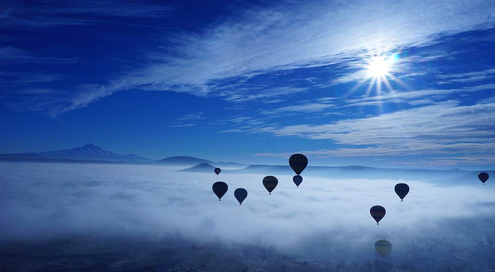 Hot air balloons rising amidst the clouds.